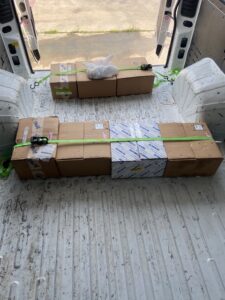 Two rows of small boxed packages strapped to the floor of a van