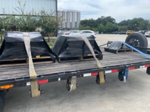 Three rows of plastic-wrapped packages strapped down to a flat bed